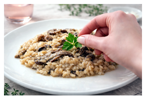 Mano che appoggia un ciuffo di prezzemolo su un risotto con i funghi
